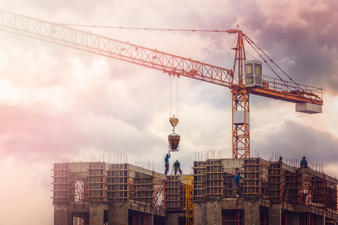 Workers on a construction site using a crane to lift materials.