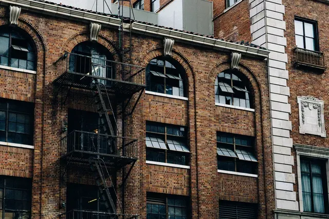 Old brick building with arched windows and external fire escape.